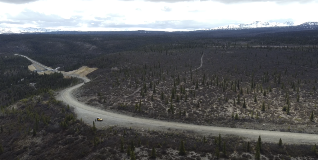 Image of a lengthy, deserted road with a car in motion.